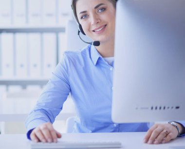 Ofisinde kulaklık takmış, telefon operatörü olarak çalışan ciddi ve güzel bir genç kadın.