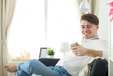 Yakışıklı genç adam dizüstü bilgisayarda oturuyor ve çalışıyor.