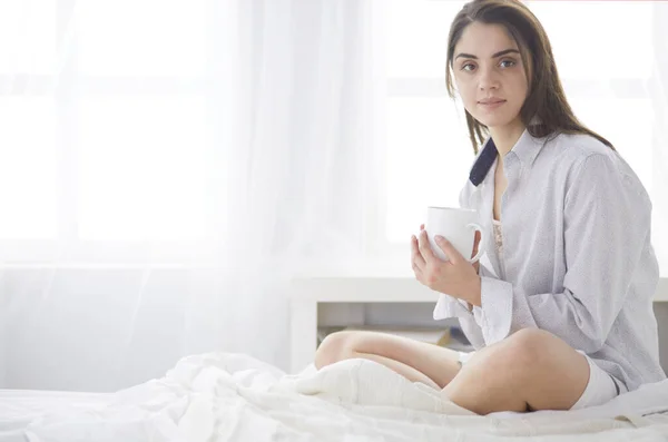 Mujer sentada en la cama leyendo un libro y desayunando — Foto de Stock