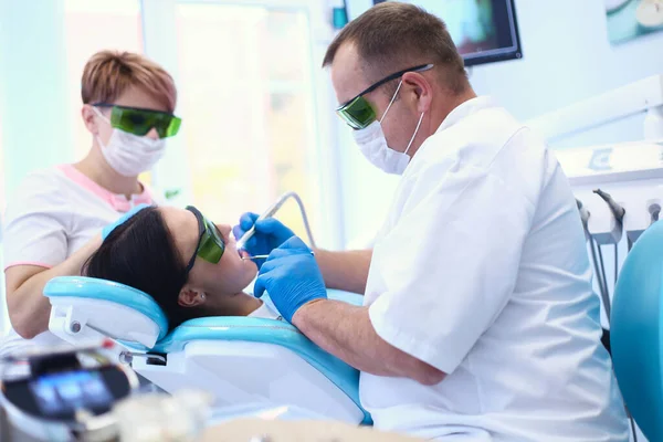 Portrait of a dentist who treats teeth of young woman patient — Stock Photo, Image