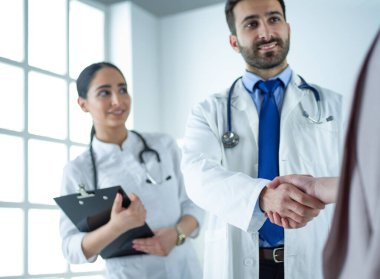 Profesyonel doktorlar hastanede el sıkışıyor, birlikte duruyorlar.