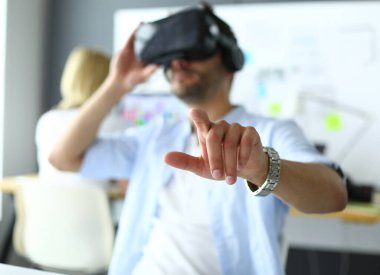 Genç erkek yazılım programcısı ofiste üç boyutlu sanal gerçeklik gözlükleriyle yeni bir uygulama test ediyor..