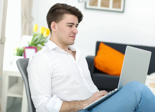 Bello giovane seduto e al lavoro sul computer portatile — Foto Stock