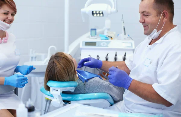 Médico dentista sênior em consultório odontológico conversando com paciente do sexo feminino e se preparando para o tratamento — Fotografia de Stock