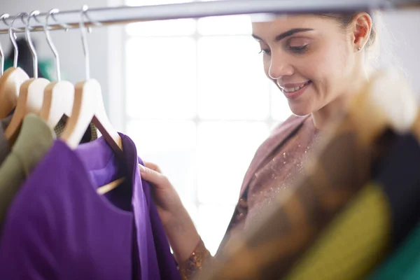 Mooie jonge stylist bij rek met hangers — Stockfoto