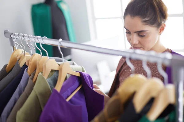 Bella giovane stilista vicino rack con appendini — Foto Stock