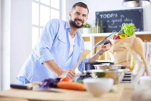 Чоловік слідує рецепту на цифровому планшеті і готує смачну і здорову їжу на кухні вдома — стокове фото