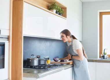 Mutfakta yemek yapmak için tablet bilgisayar kullanan genç bir kadın.