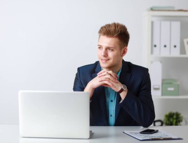 Yakışıklı genç adam dizüstü bilgisayarda oturuyor ve çalışıyor.