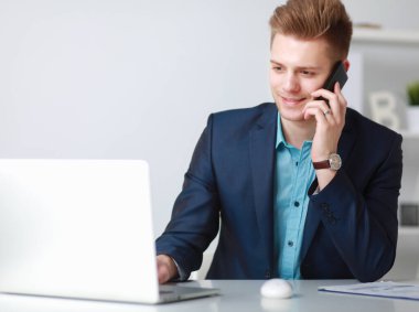 Yakışıklı genç adam dizüstü bilgisayarda oturuyor ve çalışıyor.