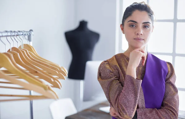 Beautiful young stylist near rack with hangers — Stock Photo, Image