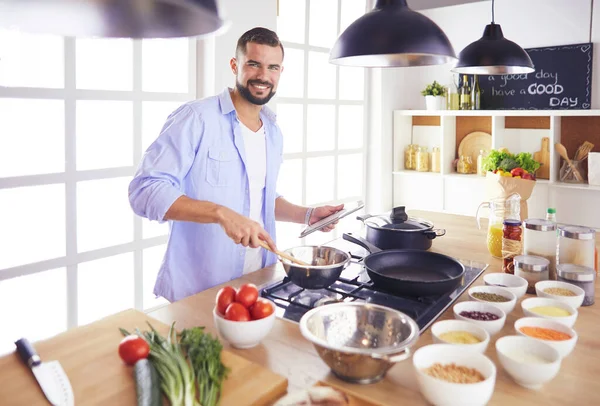Człowiek po przepis na cyfrową tabletkę i gotowanie smaczne i zdrowe jedzenie w kuchni w domu — Zdjęcie stockowe