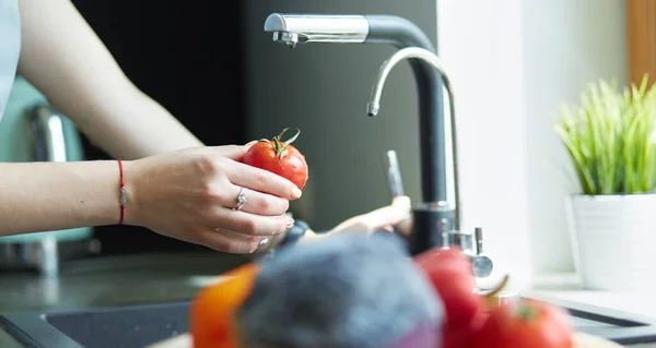 Kvinna tvätta tomater i diskbänk på nära håll — Stockfoto