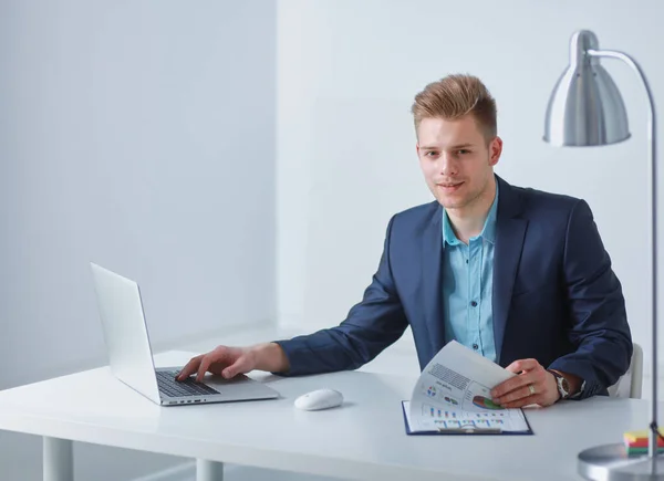Yakışıklı genç adam dizüstü bilgisayarda oturuyor ve çalışıyor. — Stok fotoğraf