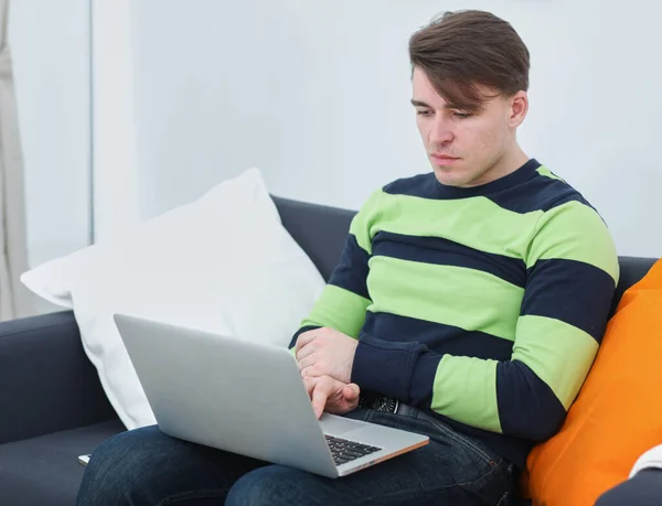 Snygg ung man sitter och arbetar på bärbar dator — Stockfoto