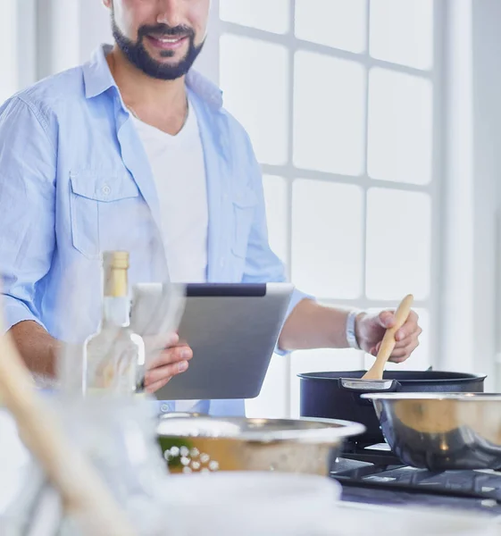 Hombre siguiendo la receta en la tableta digital y cocinar comida sabrosa y saludable en la cocina en casa — Foto de Stock