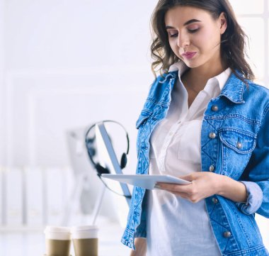 Gülümseyen kadın kahve içiyor ve kafede tablet kullanıyor.