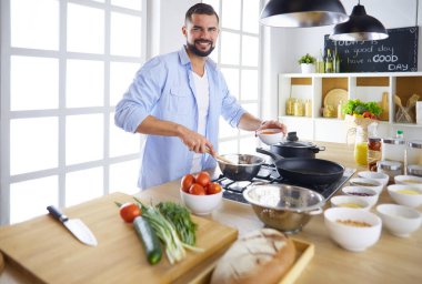 Dijital tablet ve yemek pişirme tarifine uyan bir adam evdeki mutfakta lezzetli ve sağlıklı yemekler pişiriyor.
