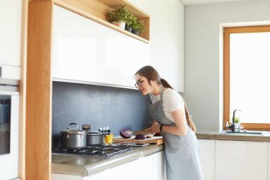 Mutfakta yemek yapmak için tablet bilgisayar kullanan genç bir kadın.