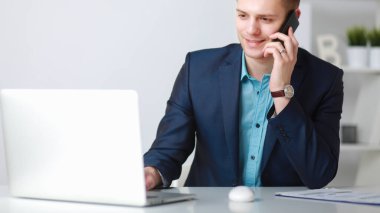 Yakışıklı genç adam dizüstü bilgisayarda oturuyor ve çalışıyor.