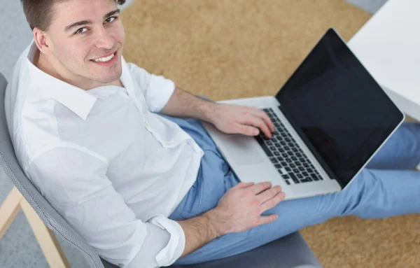 Bello giovane seduto e al lavoro sul computer portatile — Foto Stock