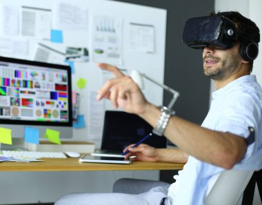 Genç erkek yazılım programcısı ofiste üç boyutlu sanal gerçeklik gözlükleriyle yeni bir uygulama test ediyor..