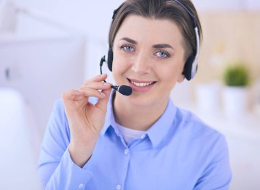 Ofisinde kulaklık takmış, telefon operatörü olarak çalışan ciddi ve güzel bir genç kadın.