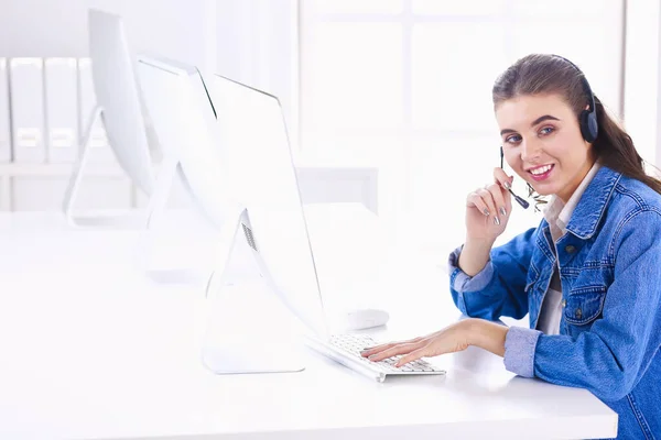 Glimlachende zakenvrouw met headset met behulp van laptop aan de balie in werk — Stockfoto