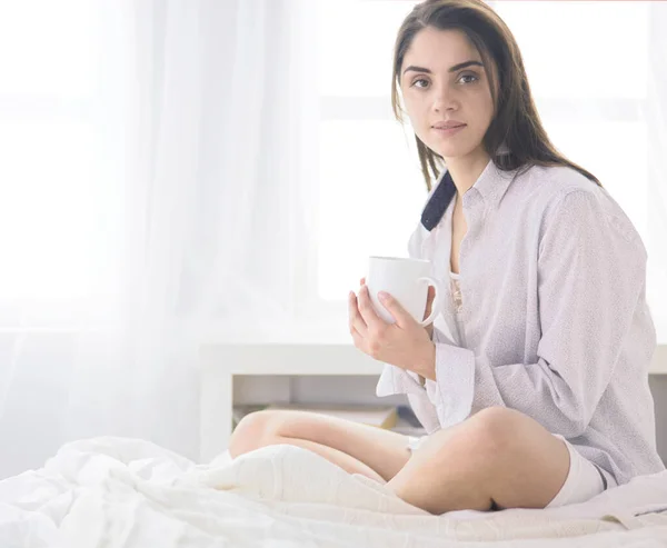 Mulher sentada na cama lendo um livro e tomando café da manhã — Fotografia de Stock