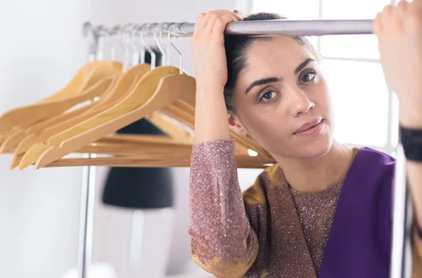 Mooie jonge stylist bij rek met hangers — Stockfoto