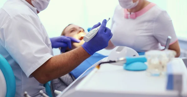 Retrato de un dentista que trata los dientes de una paciente joven — Foto de Stock