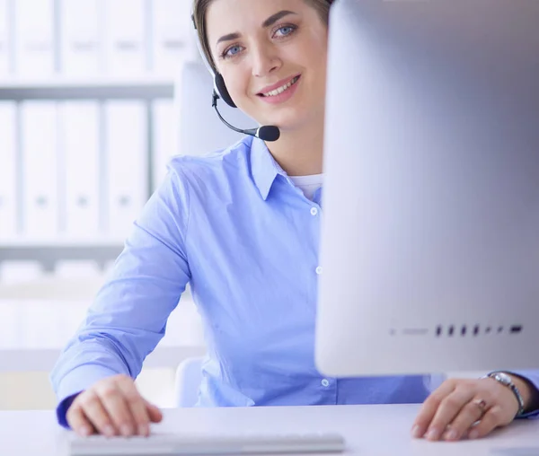 Ernstige mooie jonge vrouw die werkt als support telefoon operator met headset in het kantoor — Stockfoto