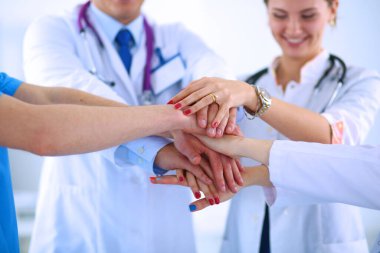 Doktorlar ve hemşireler tıbbi bir ekipte el ele tutuşuyorlar.