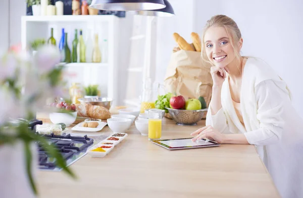 Hermosa joven usando una tableta digital en la cocina — Foto de Stock