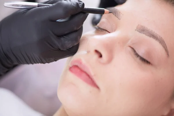 Cosmetólogo aplicando maquillaje permanente en las cejas —  Fotos de Stock