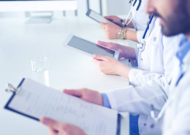 Toplantıdaki doktorlar, masanın üstünde oturuyorlar.
