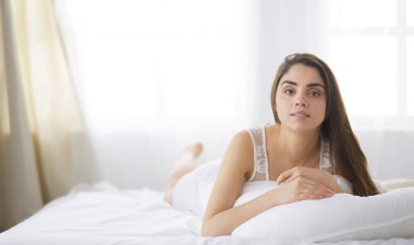 Güzel bir kadın yatağında uzanıyor.