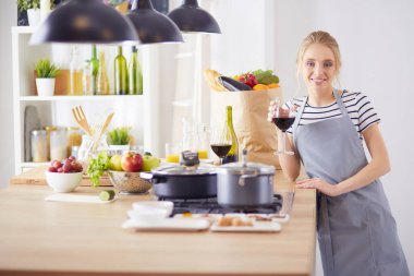 Güzel kadın mutfakta şarap içiyor.