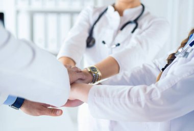 Doktorlar ve hemşireler tıbbi bir ekipte el ele tutuşuyorlar.