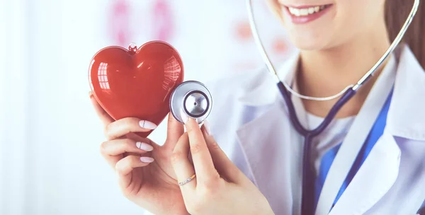 Médica com estetoscópio segurando coração, em fundo claro — Fotografia de Stock