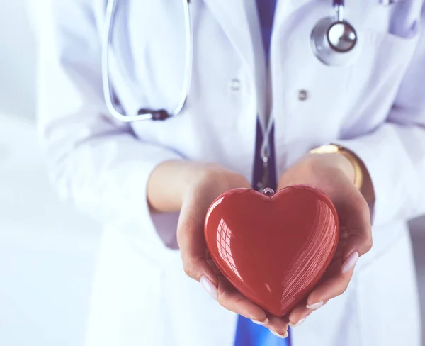 Female doctor with stethoscope holding heart, on light background — Stock Photo, Image