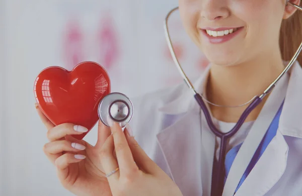 Un médecin avec stéthoscope examinant le cœur rouge, isolé sur blanc — Photo