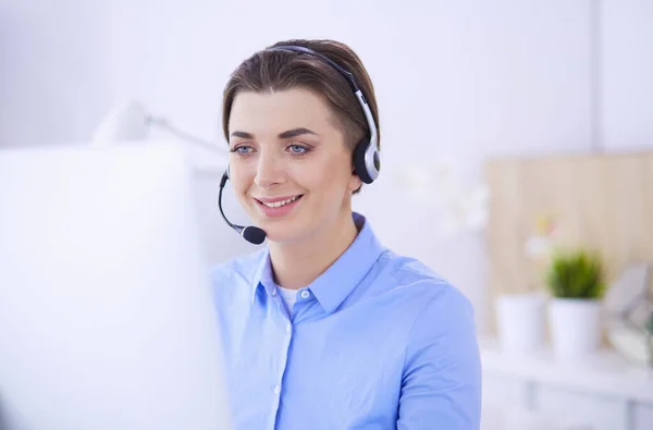 Ernstige mooie jonge vrouw die werkt als support telefoon operator met headset in het kantoor — Stockfoto