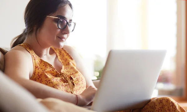 Giovane donna seduta sul divano che lavora sul computer portatile a casa — Foto Stock