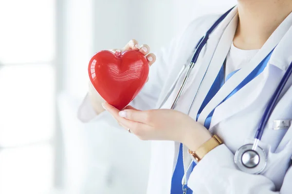 Medico femminile con stetoscopio che tiene il cuore, su sfondo chiaro — Foto Stock