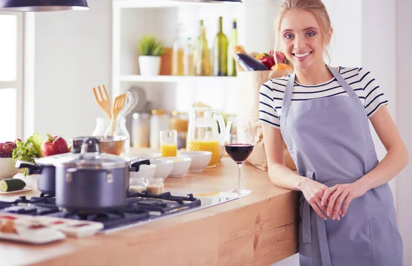 Mulher bonita bebendo um pouco de vinho em casa na cozinha — Fotografia de Stock