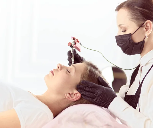 Jonge vrouw ondergaat procedure van wenkbrauw permanente make-up in schoonheidssalon — Stockfoto