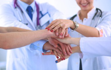Doktorlar ve hemşireler tıbbi bir ekipte el ele tutuşuyorlar.