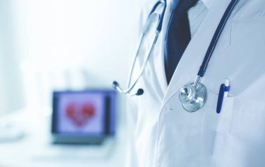 Yakışıklı doktor genç bayan hastasıyla konuşuyor ve ofisinde otururken notlar alıyor..