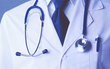 Yakışıklı doktor genç bayan hastasıyla konuşuyor ve ofisinde otururken notlar alıyor..